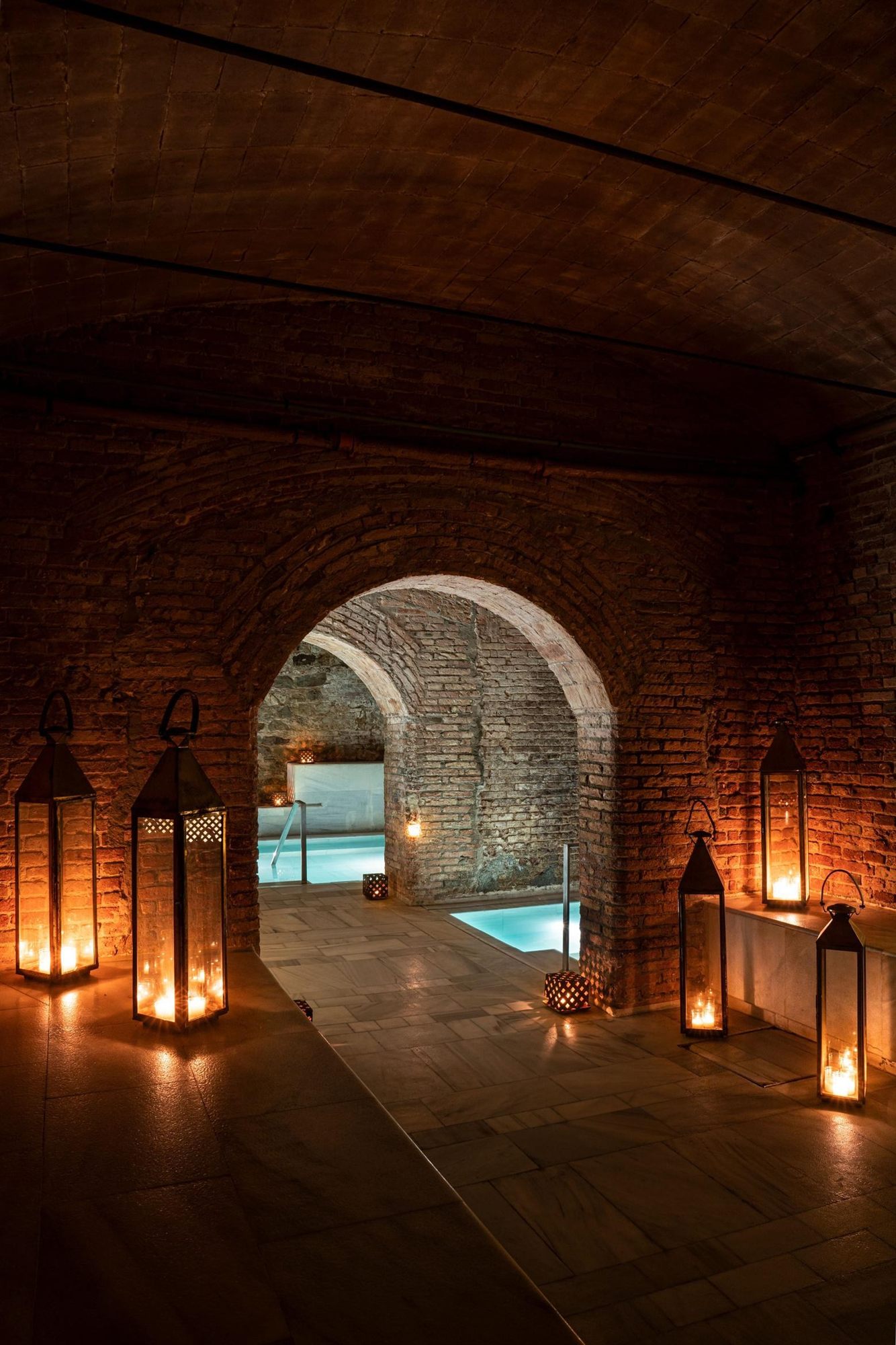 Pasillo de arcos iluminado con velas en AIRE Ancient Baths