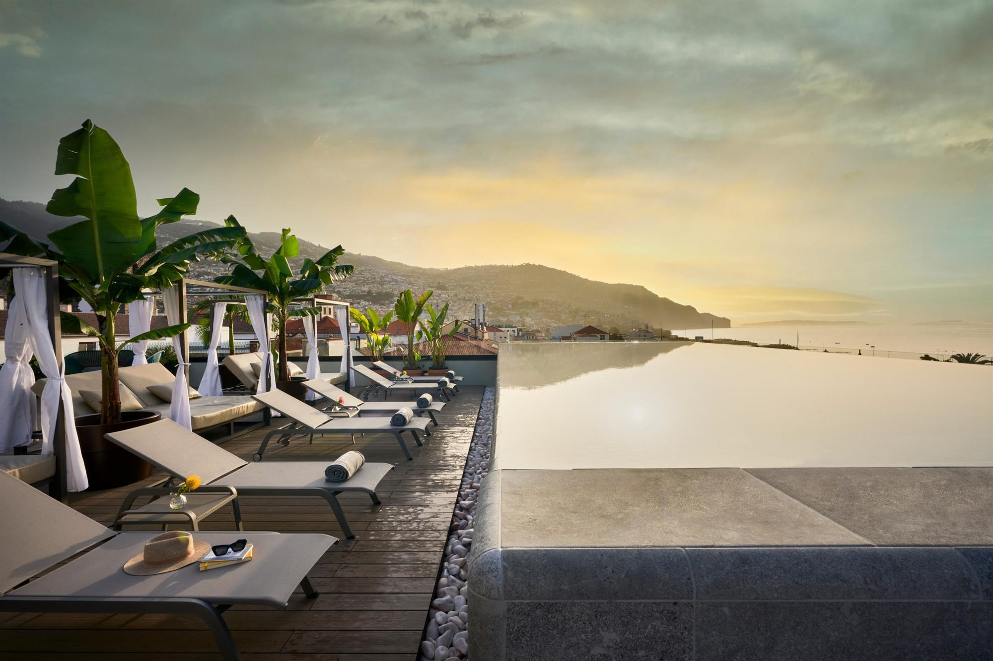 Piscina infinity con tumbonas al atardecer en Barcel&oacute; Funchal Oldtown
