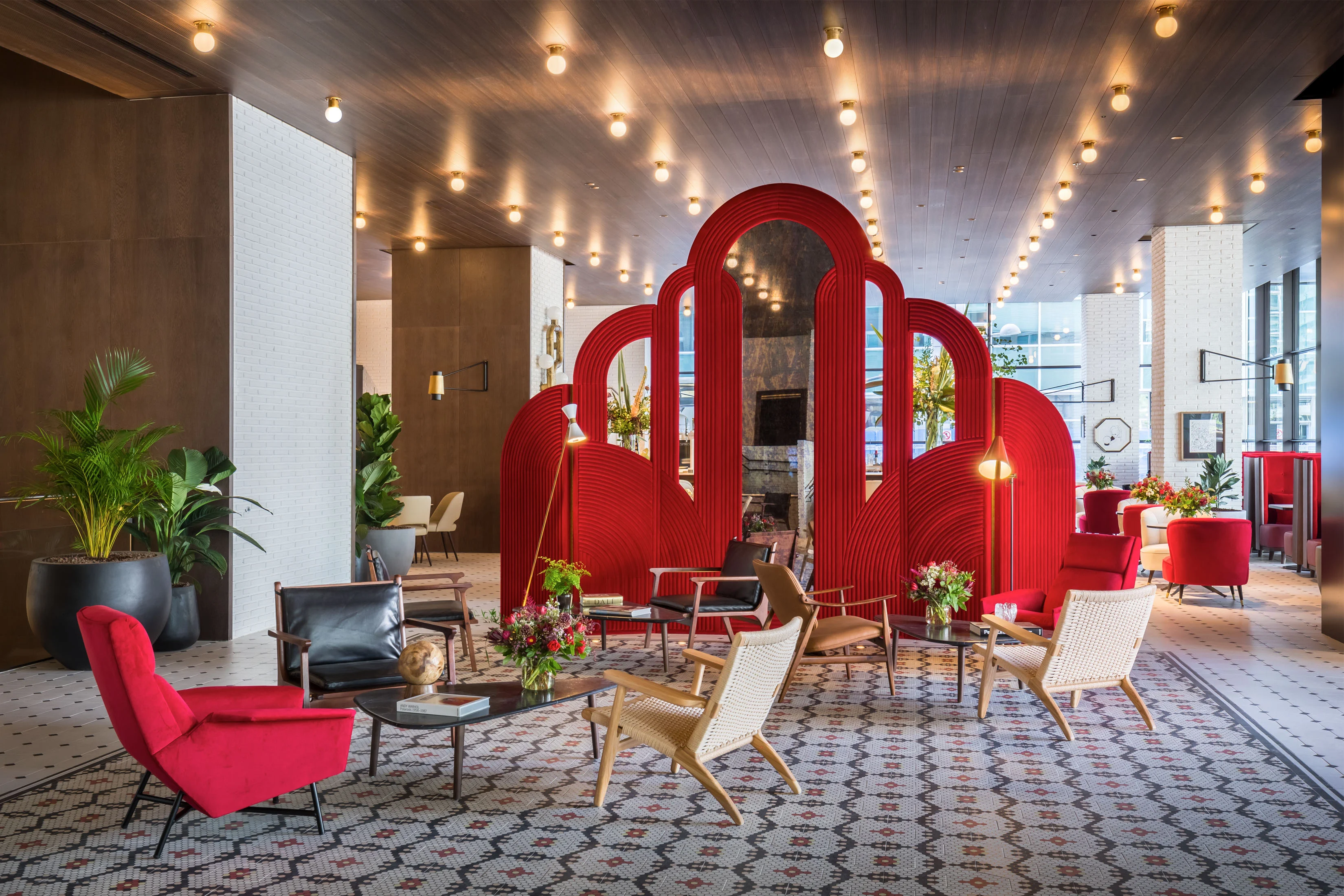 Lobby de Esc&aacute;ndalo con grandes arcos rojos teatrales y sillones blancos y rojos