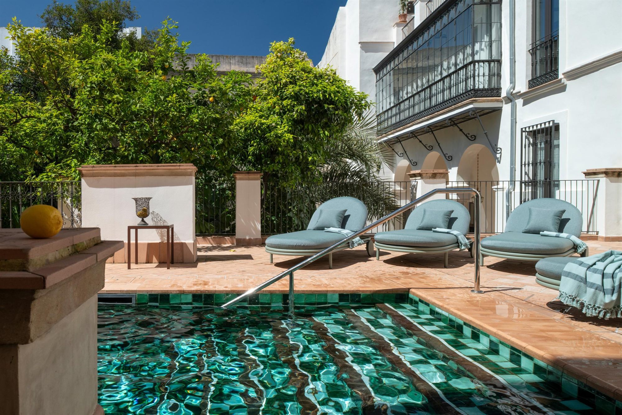 Piscina exterior con azulejos verdes y tumbonas turquesa del Hotel La Casa del Limonero