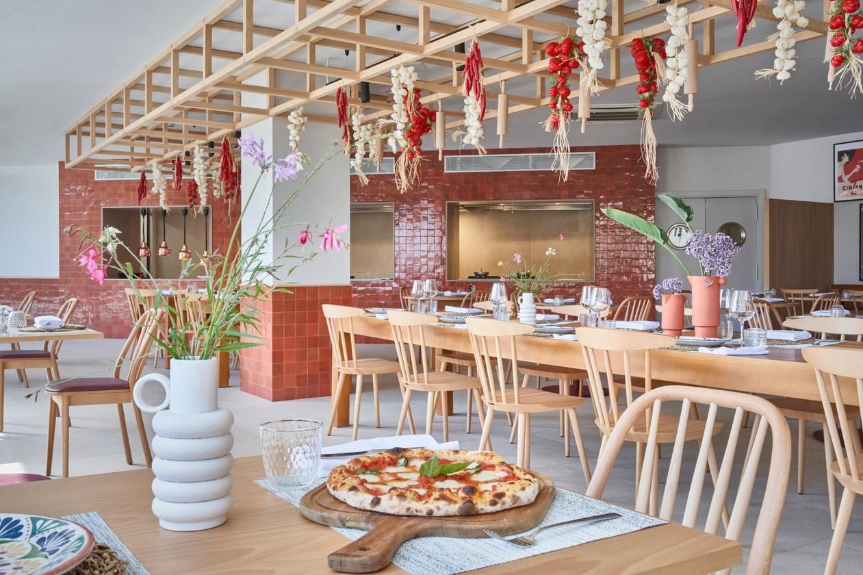 Comedor de La Dolce Vita con ristras de guindillas colgadas y mesas de madera