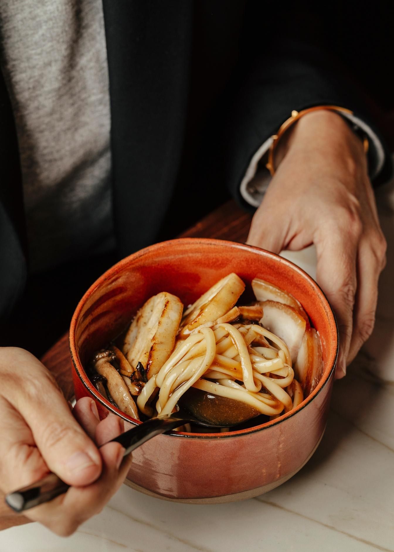 Manos sosteniendo cuenco con udon