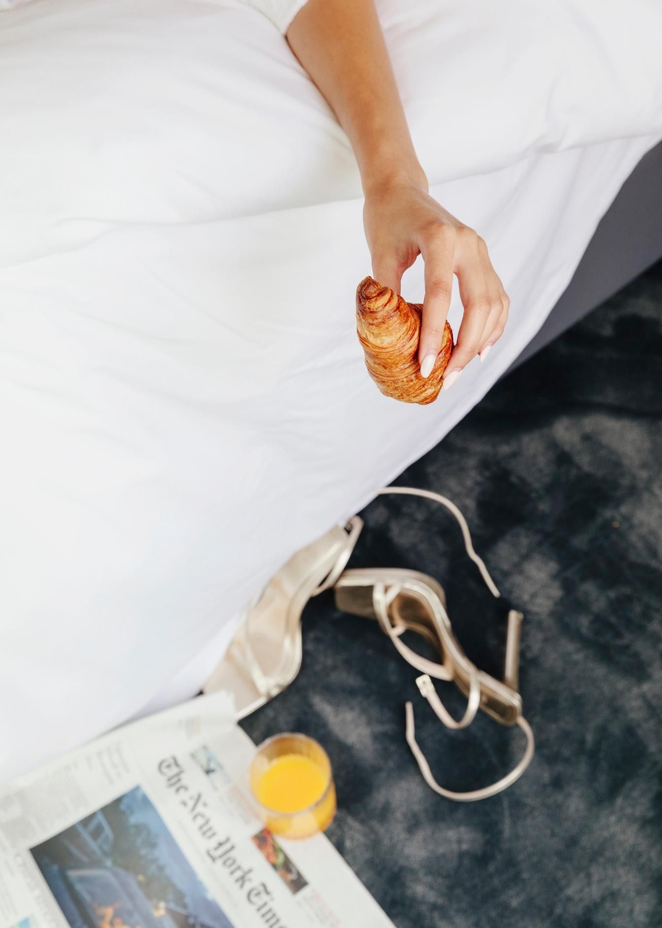 Detalle de mano sosteniendo croissant en el desayuno