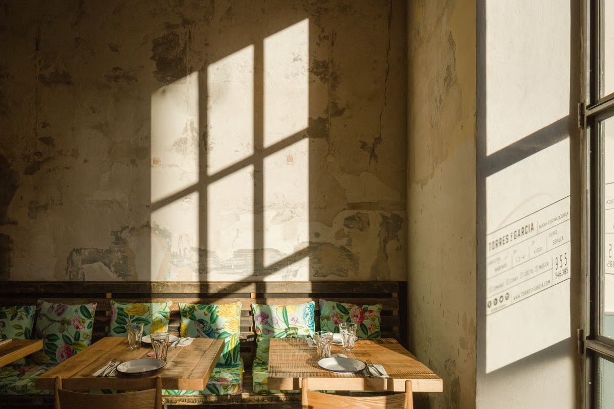 Ventanas con luz natural y mesa de madera en Torres y Garc&iacute;a