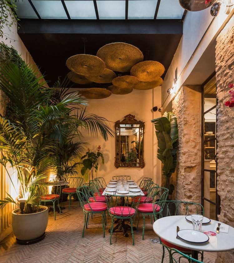 Patio verde con mesas rojas de Torres y Garc&iacute;a