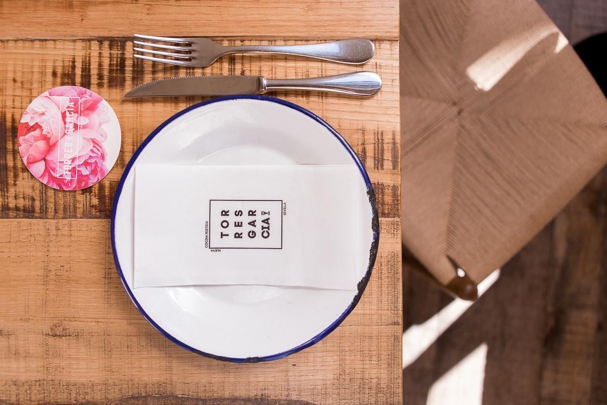 Mesa con plato, cubiertos y servilleta con logo Torres y Garc&iacute;a