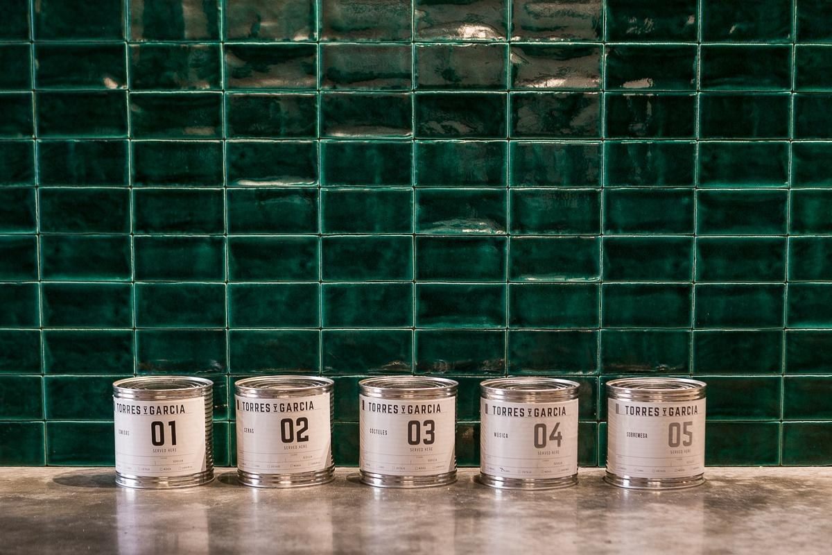 Pared de azulejos verdes con latas numeradas Torres y Garc&iacute;a